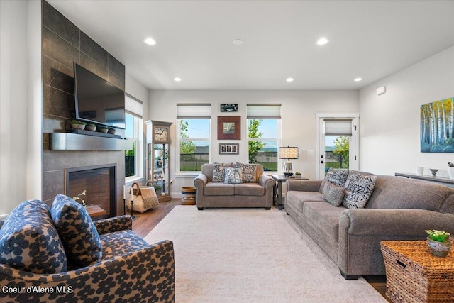 living room with a tiled fireplace and light hardwood / wood-style flooring