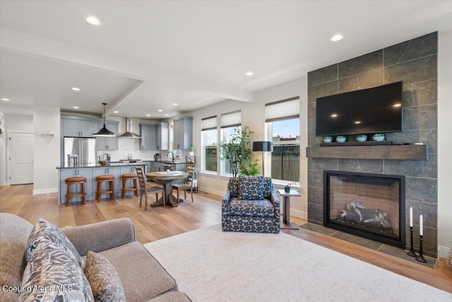 living room with sink, light hardwood / wood-style flooring, and a tile fireplace