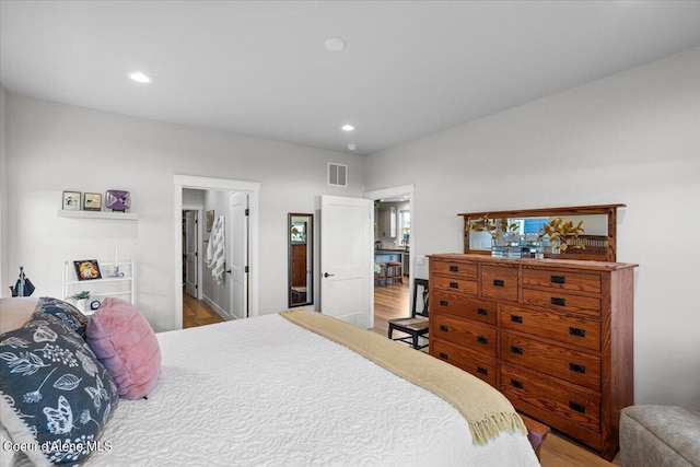 bedroom featuring ensuite bath and hardwood / wood-style floors