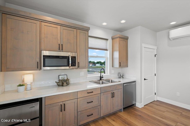 kitchen featuring stainless steel appliances, a wall mounted AC, light wood-type flooring, and sink