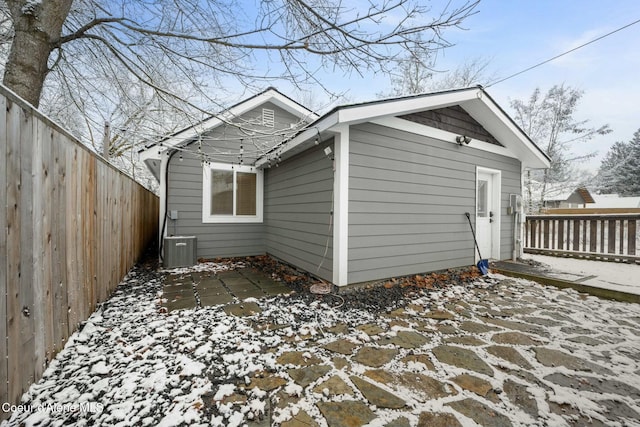 snow covered property with central air condition unit and a patio area