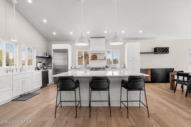 kitchen with sink, a kitchen island, custom range hood, and white cabinetry