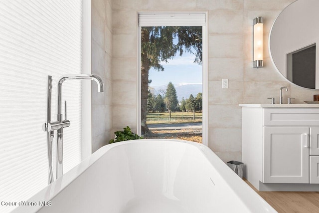 bathroom with tile walls, a tub, and vanity