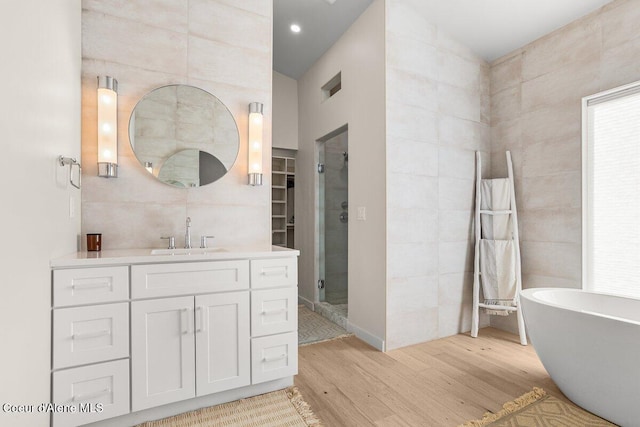 bathroom with tile walls, vanity, independent shower and bath, and hardwood / wood-style floors