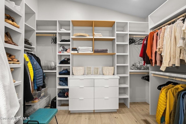 spacious closet with light hardwood / wood-style flooring and vaulted ceiling