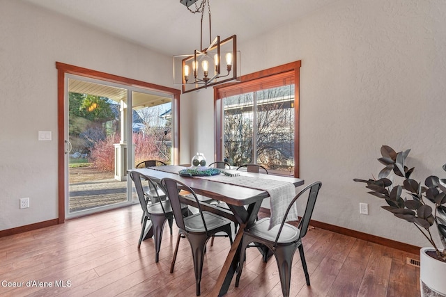 dining area featuring a healthy amount of sunlight, an inviting chandelier, and hardwood / wood-style flooring