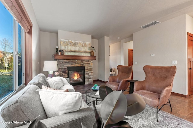 living room with wood-type flooring and a stone fireplace