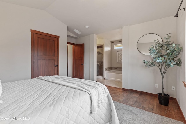 bedroom with lofted ceiling, ensuite bath, and light wood-type flooring