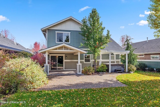 view of front of home with a front lawn, a hot tub, a pergola, and a patio