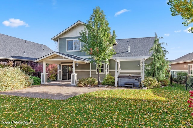 back of property featuring a patio area, a hot tub, and a lawn