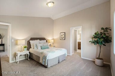 bedroom with ensuite bath, light carpet, and lofted ceiling