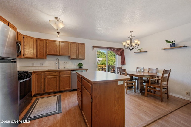 kitchen with light hardwood / wood-style flooring, pendant lighting, a center island, appliances with stainless steel finishes, and sink