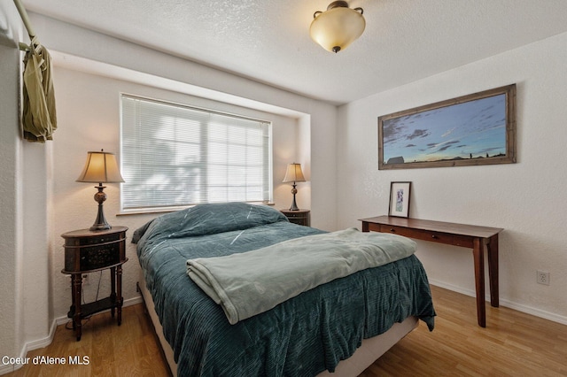 bedroom with a textured ceiling and hardwood / wood-style flooring