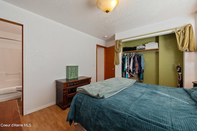 bedroom featuring a textured ceiling, connected bathroom, a closet, and hardwood / wood-style flooring