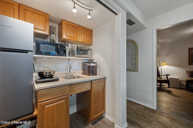 kitchen with sink, dark hardwood / wood-style flooring, and stainless steel refrigerator