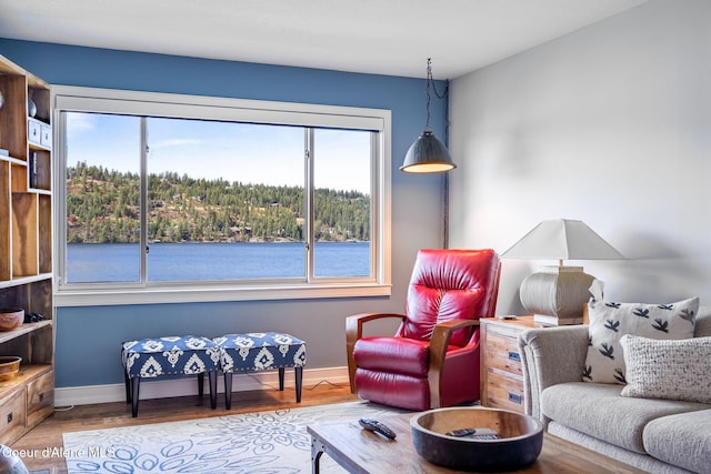 living area with a water view, plenty of natural light, and hardwood / wood-style flooring