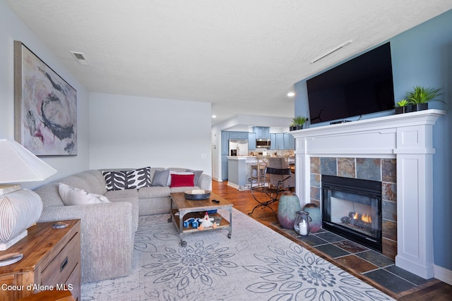 living room with a fireplace, dark wood-type flooring, and a textured ceiling