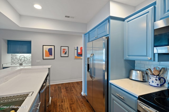 kitchen featuring blue cabinets, appliances with stainless steel finishes, dark hardwood / wood-style flooring, and tasteful backsplash