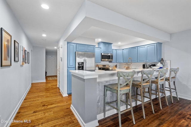 kitchen with kitchen peninsula, stainless steel appliances, blue cabinetry, and a breakfast bar area