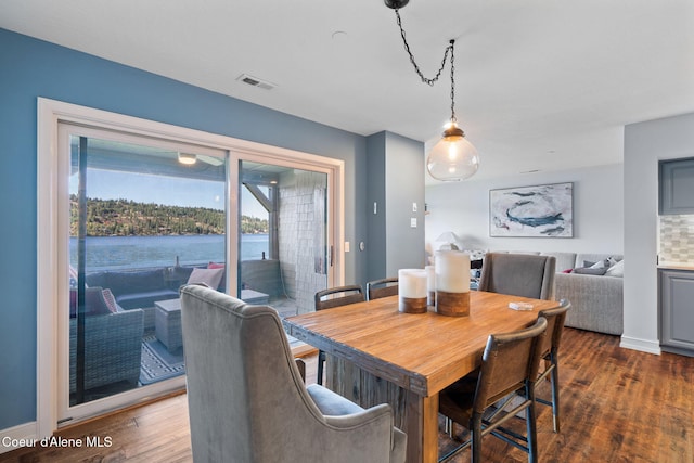 dining space featuring dark hardwood / wood-style floors and a water view