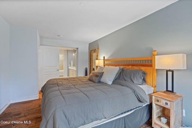 bedroom featuring connected bathroom and dark wood-type flooring