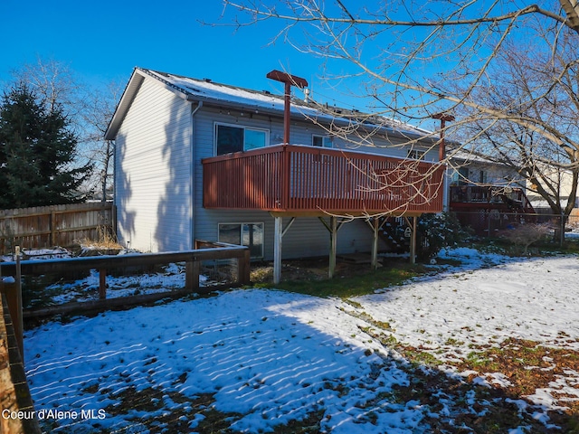 snow covered back of property featuring a deck