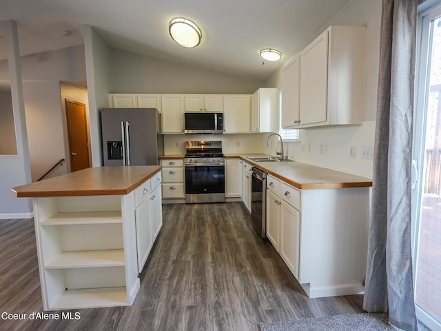 kitchen featuring appliances with stainless steel finishes, lofted ceiling, white cabinetry, plenty of natural light, and sink