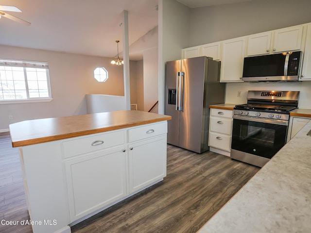 kitchen featuring pendant lighting, white cabinets, dark hardwood / wood-style flooring, stainless steel appliances, and vaulted ceiling