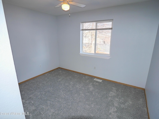 empty room with ceiling fan and dark carpet