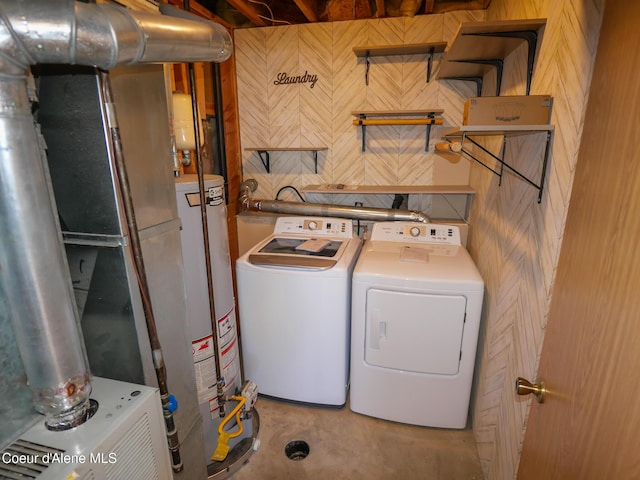 clothes washing area featuring gas water heater, washing machine and dryer, and wooden walls