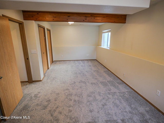 carpeted spare room featuring beam ceiling