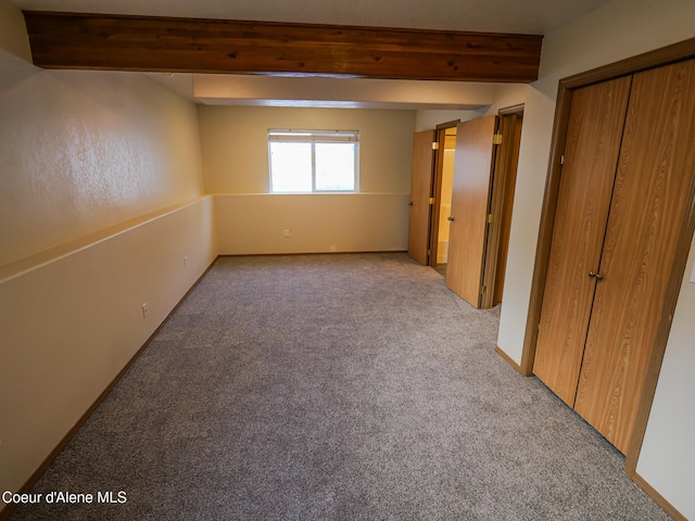 interior space featuring light carpet, a closet, and beamed ceiling