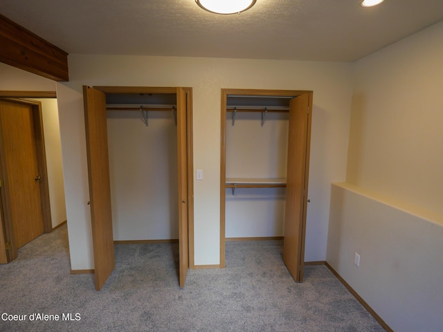 unfurnished bedroom featuring light carpet and two closets