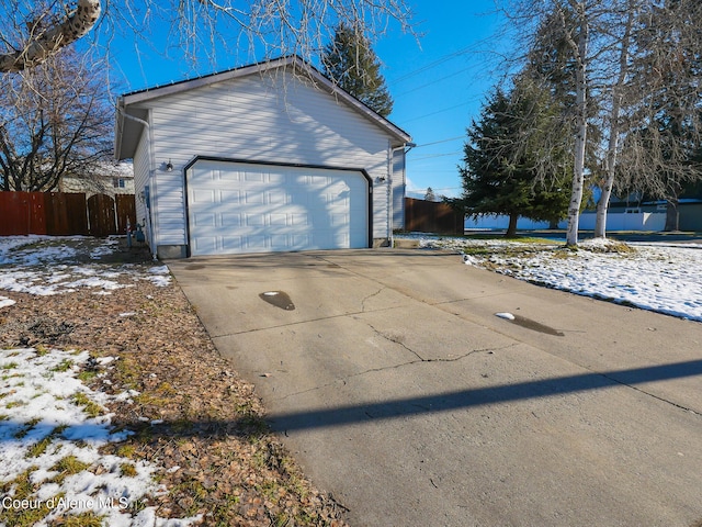 view of snowy exterior with a garage and an outbuilding