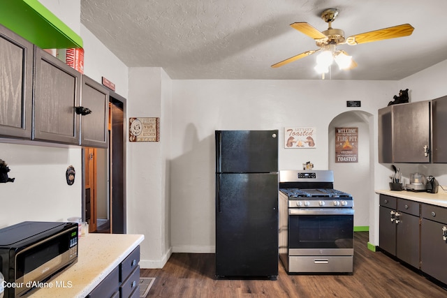 kitchen with dark brown cabinets, black refrigerator, stainless steel range with gas stovetop, dark hardwood / wood-style flooring, and a textured ceiling