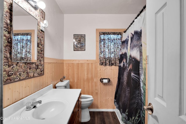 bathroom featuring vanity, toilet, wooden walls, and hardwood / wood-style flooring