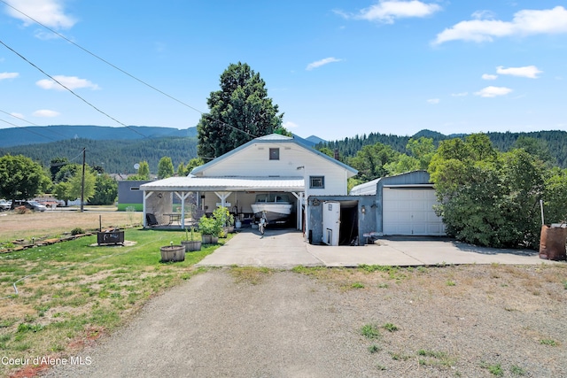 view of front facade with an outbuilding, a porch, a garage, a front yard, and a mountain view