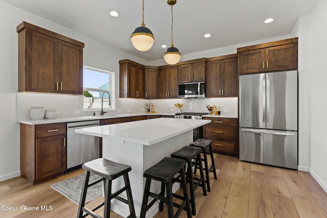 kitchen featuring sink, tasteful backsplash, appliances with stainless steel finishes, a kitchen breakfast bar, and a kitchen island