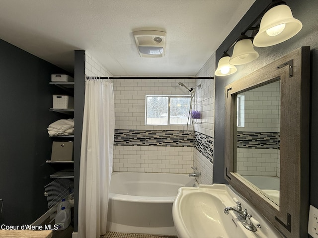 bathroom featuring shower / bathtub combination with curtain, a textured ceiling, and sink