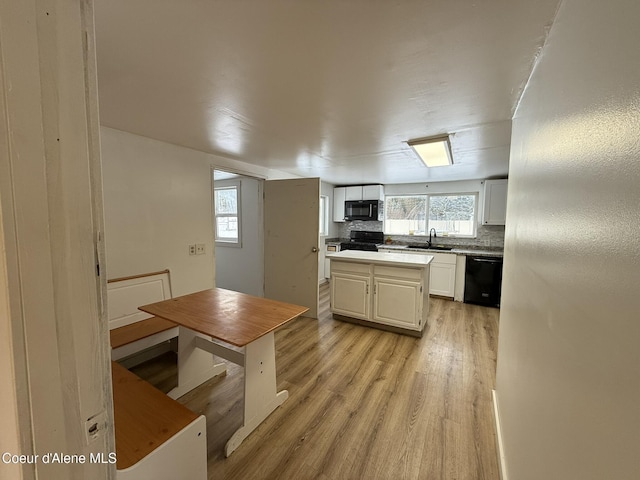 kitchen featuring tasteful backsplash, black appliances, light hardwood / wood-style floors, white cabinets, and sink