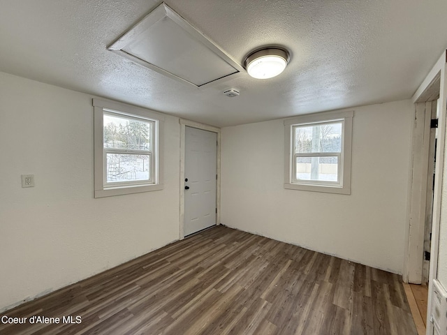 spare room featuring a textured ceiling and dark hardwood / wood-style flooring