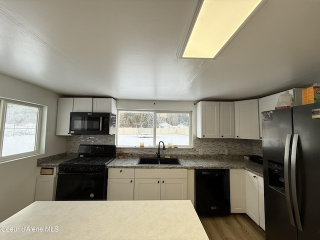 kitchen featuring sink, white cabinets, decorative backsplash, and black appliances