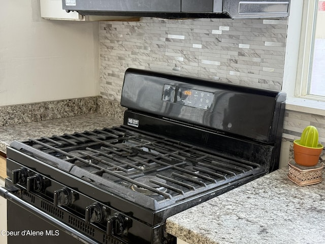 room details featuring tasteful backsplash, light stone countertops, and black gas range oven