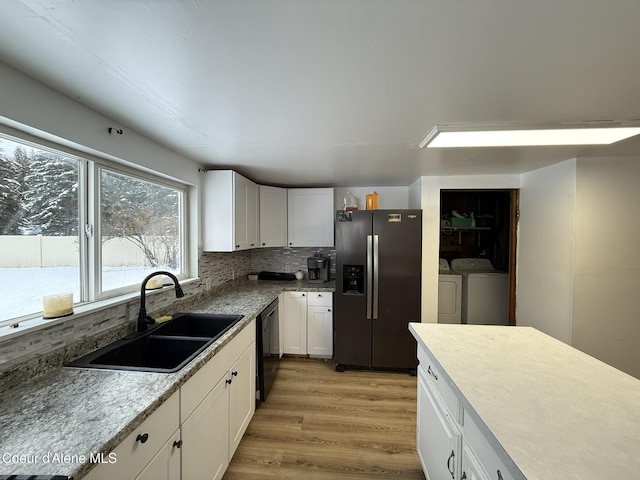 kitchen featuring white cabinets, stainless steel fridge, sink, washer and clothes dryer, and backsplash