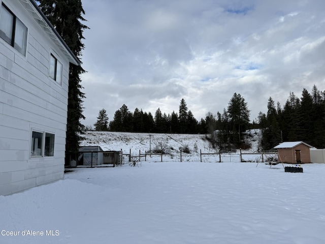 snowy yard with a storage shed