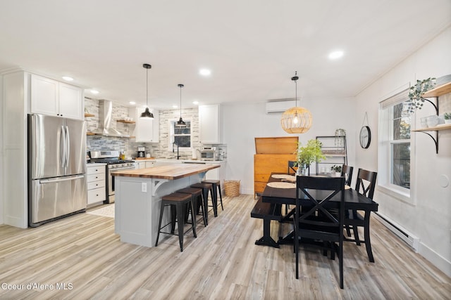 dining space featuring a wall unit AC, a baseboard radiator, light wood-type flooring, and ornamental molding