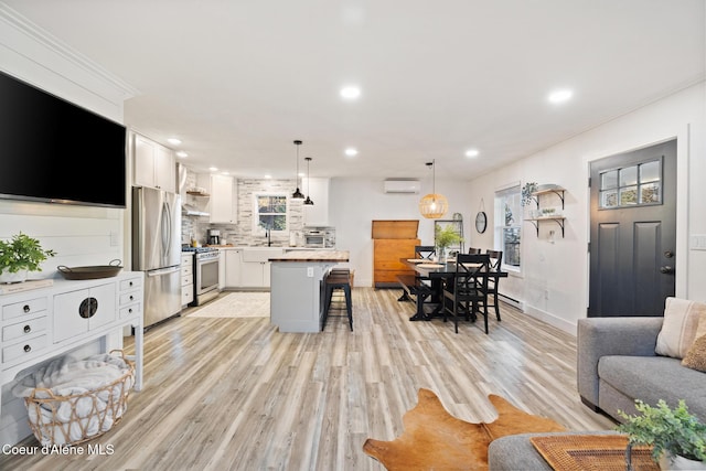 living room with a baseboard heating unit, light wood-type flooring, a wall mounted air conditioner, and sink