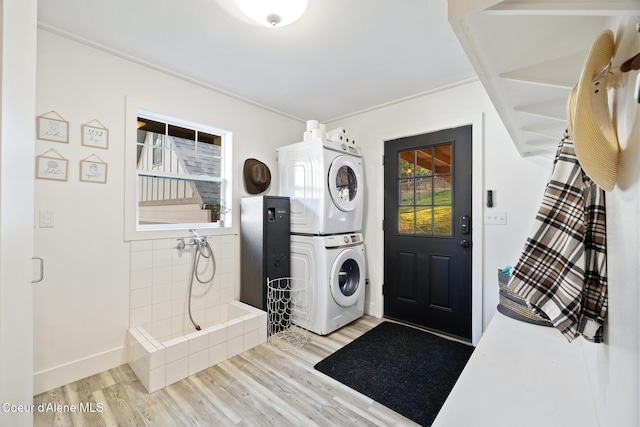 clothes washing area featuring stacked washer and dryer and light wood-type flooring