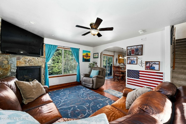 living room featuring dark wood-type flooring, a fireplace, and ceiling fan