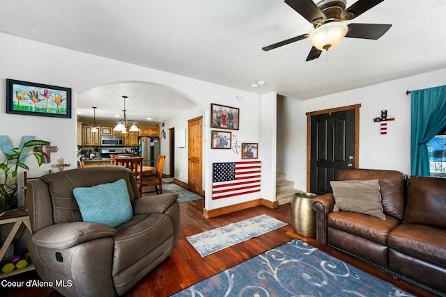 living room featuring dark wood-type flooring and ceiling fan with notable chandelier